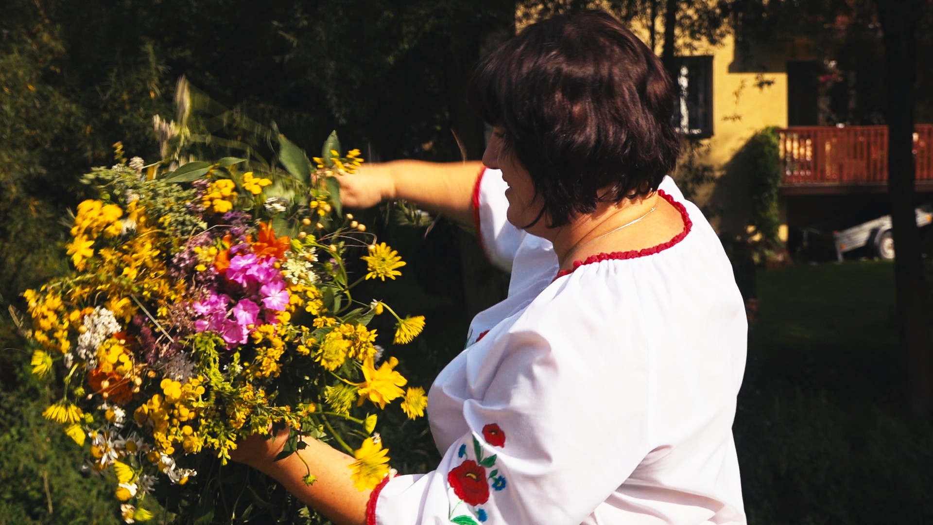 kobieta w białej bluzce układa bukiet kwiatów